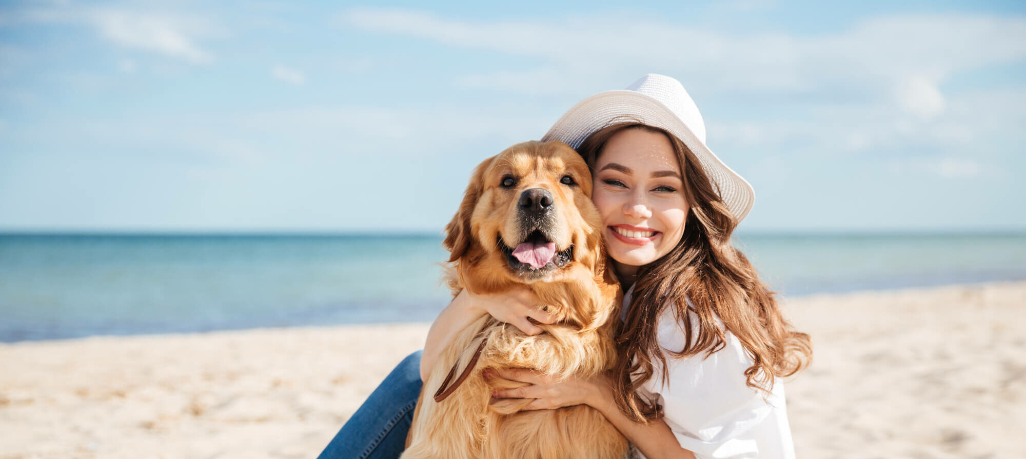 mujer con perro golden en la playa